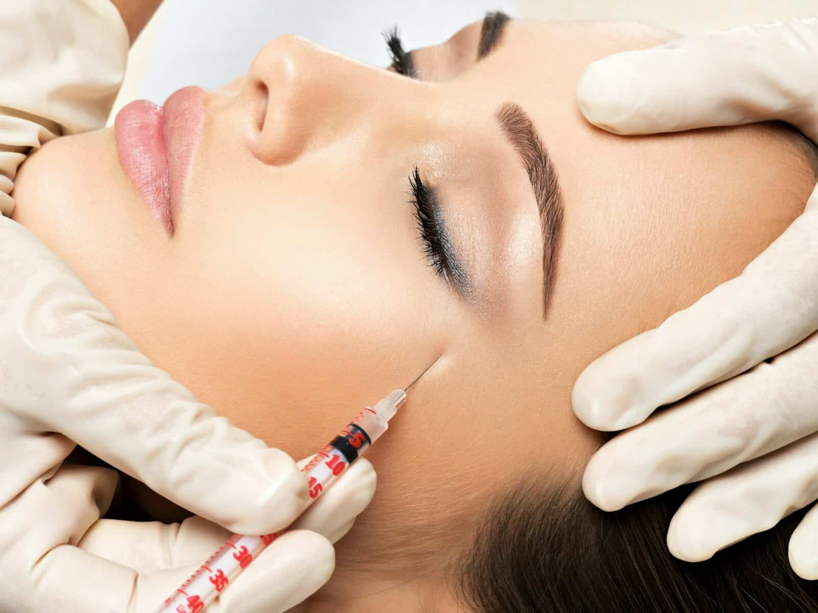 Woman getting cosmetic injection of botox near eyes